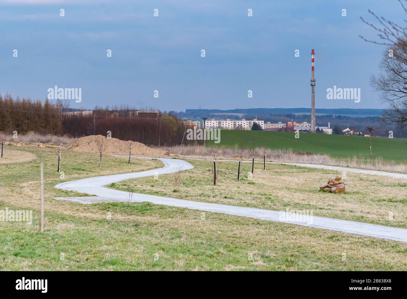 Chemin étroit menant à une petite ville avec bloc de maisons et usine avec grande cheminée Banque D'Images