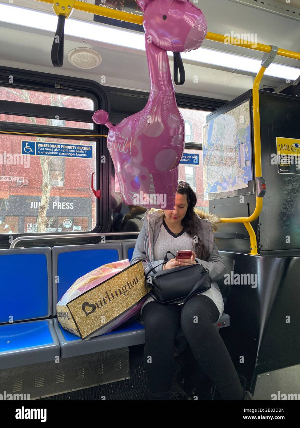 Une femme passe un New York City bus avec un cadeau de jouet pour une mère qui vient d'avoir un garçon. Brooklyn, New York. Banque D'Images