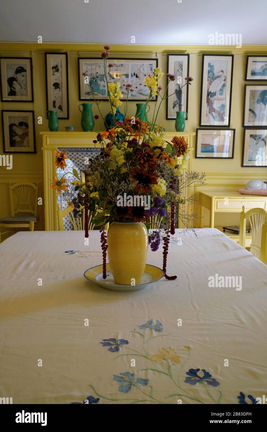 Fleurs dans un vase jaune sur la table à manger de la salle à manger jaune dans la maison de Monet. Région de Normandie. Giverny. France Banque D'Images