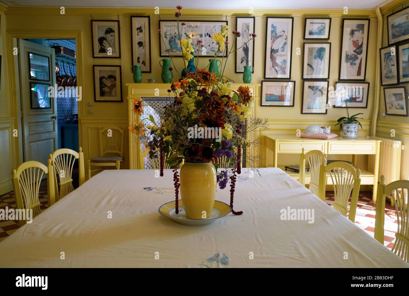 Fleurs dans un vase jaune sur la table à manger de la salle à manger jaune dans la maison de Monet. Région de Normandie. Giverny. France Banque D'Images