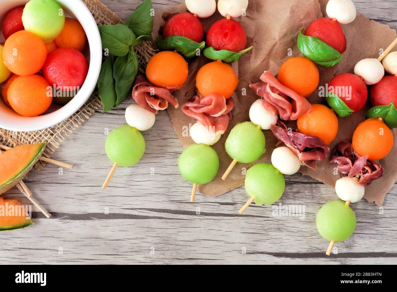 Brochettes colorées de fruits d'été avec melon, fromage et prosciutto, gros plan sur un fond en bois Banque D'Images