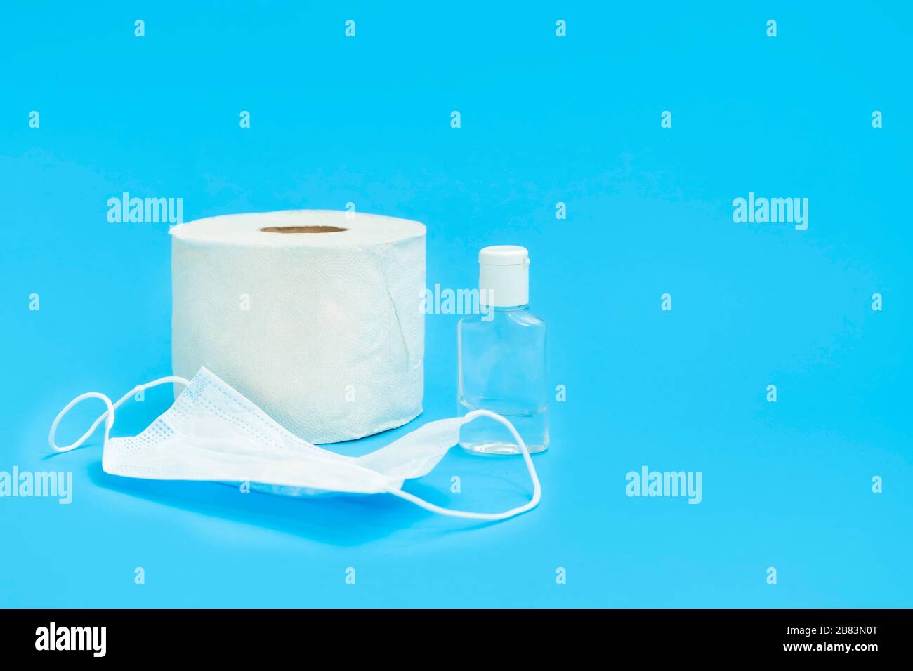 La plupart des stocks nécessaires pendant la pandémie de coronavirus : gel désinfectant pour les mains, masque facial médical, papier toilette sur fond bleu avec espace de copie Banque D'Images