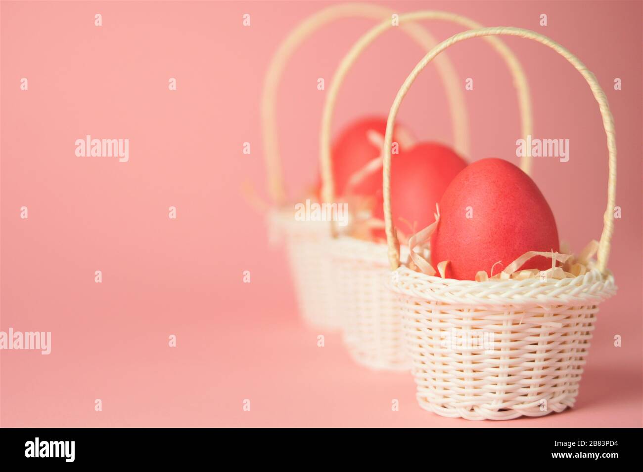 Œufs de poulet roses dans un panier en osier blanc recouvert de paille sur fond rose vif. Carte de vacances avec espace pour le texte.symbole de Pâques.espace de copie. Banque D'Images