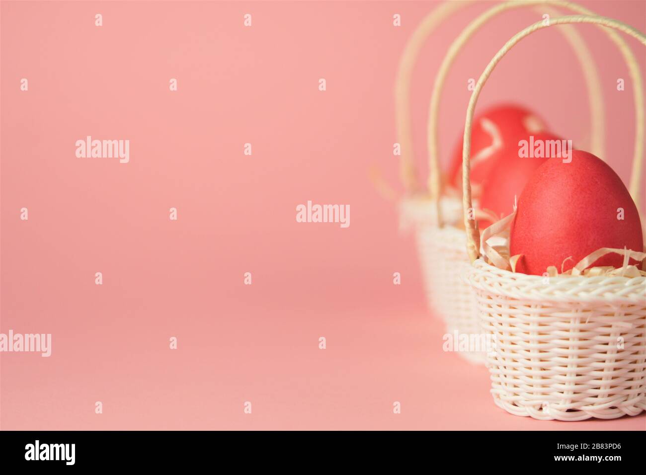 Œufs de poulet roses dans un panier en osier blanc recouvert de paille sur fond rose vif. Carte de vacances avec espace pour le texte.symbole de Pâques.espace de copie. Banque D'Images