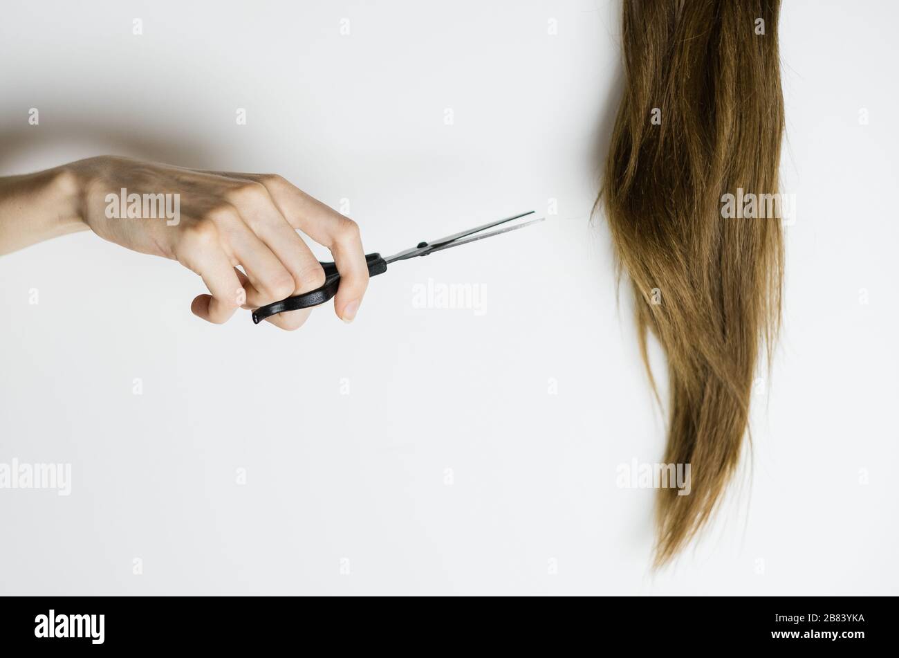 La femme bouleversée coupe ses cheveux longs et droits avec des ciseaux Banque D'Images