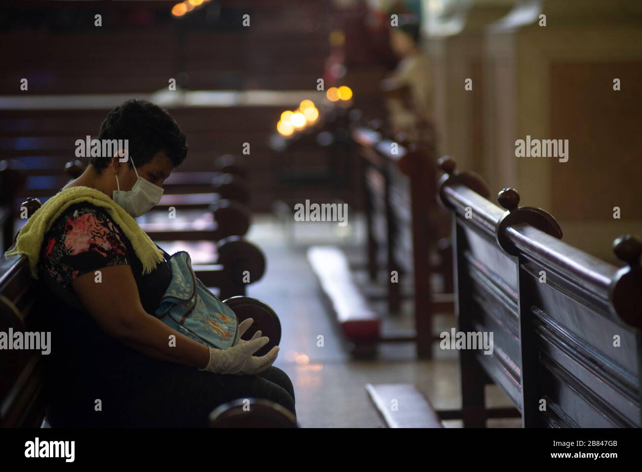 San Salvador, El Salvador. 19 mars 2020. Une femme portant un masque de visage et des gants prie à l'intérieur d'une église. Toutes les célébrations de masse ont été annulées par l'église catholique.le Président Nayib Bukele a adressé à la nation le 18 mars pour confirmer le premier cas de COVID-19 dans le pays. Crédit: Camilo Freedman/ZUMA Wire/Alay Live News Banque D'Images