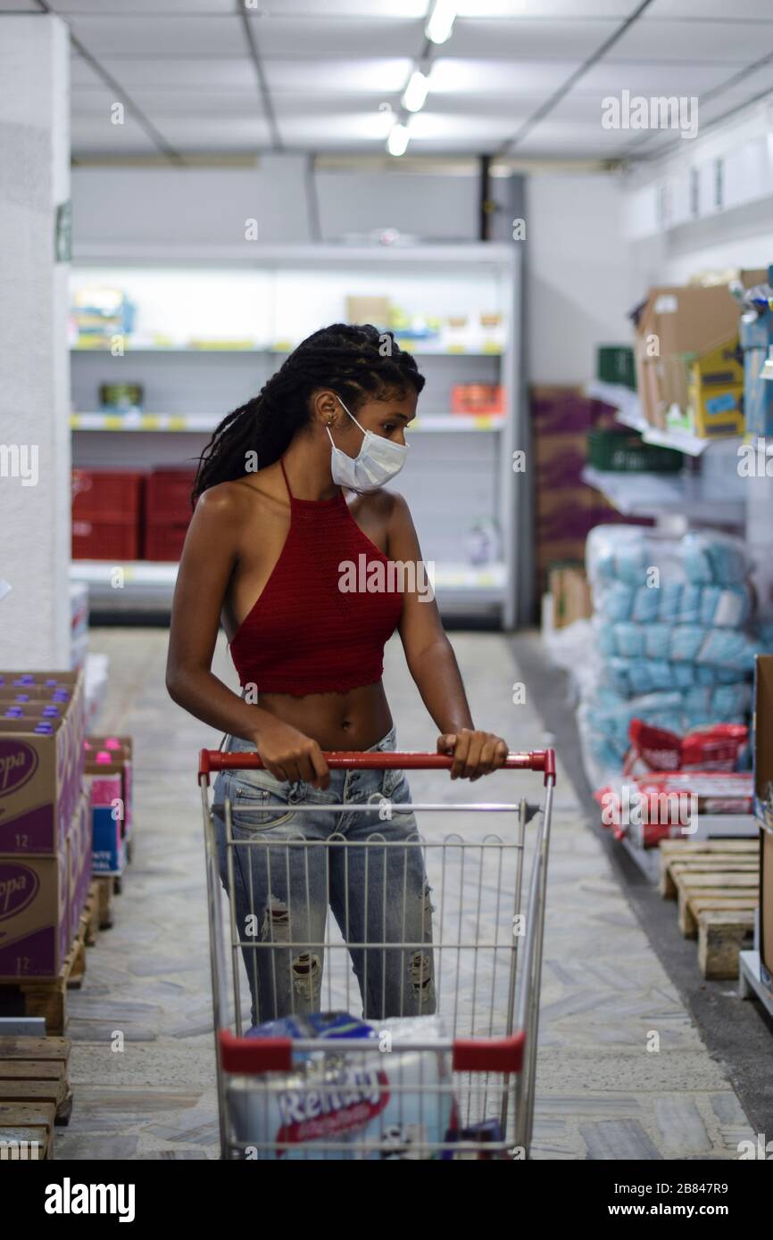 Jeune femme avec masque facial shopping de dernière minute dans un supermarché, un jour avant le premier verrouillage en Colombie en raison de Coronavirus. Banque D'Images