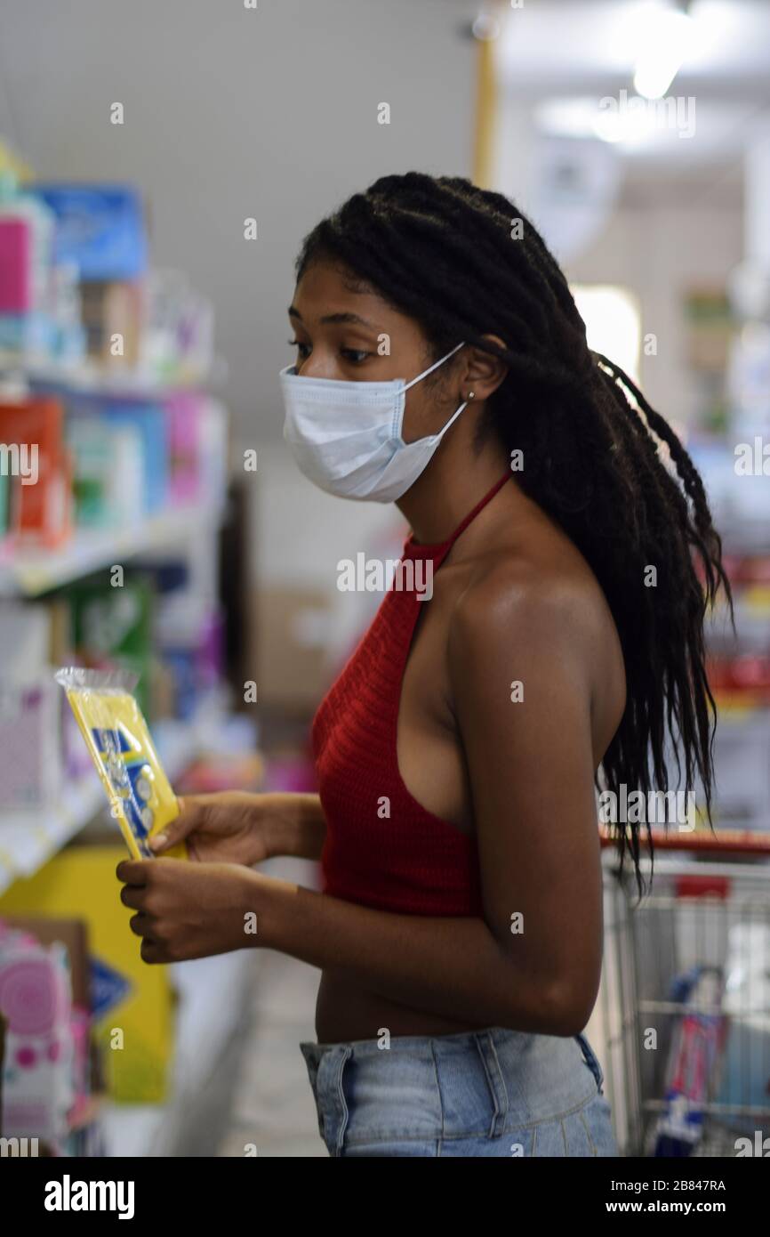 Jeune femme avec masque facial shopping de dernière minute dans un supermarché, un jour avant le premier verrouillage en Colombie en raison de Coronavirus. Banque D'Images