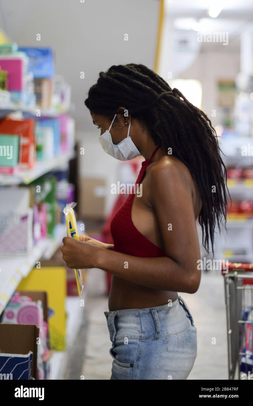 Jeune femme avec masque facial shopping de dernière minute dans un supermarché, un jour avant le premier verrouillage en Colombie en raison de Coronavirus. Banque D'Images