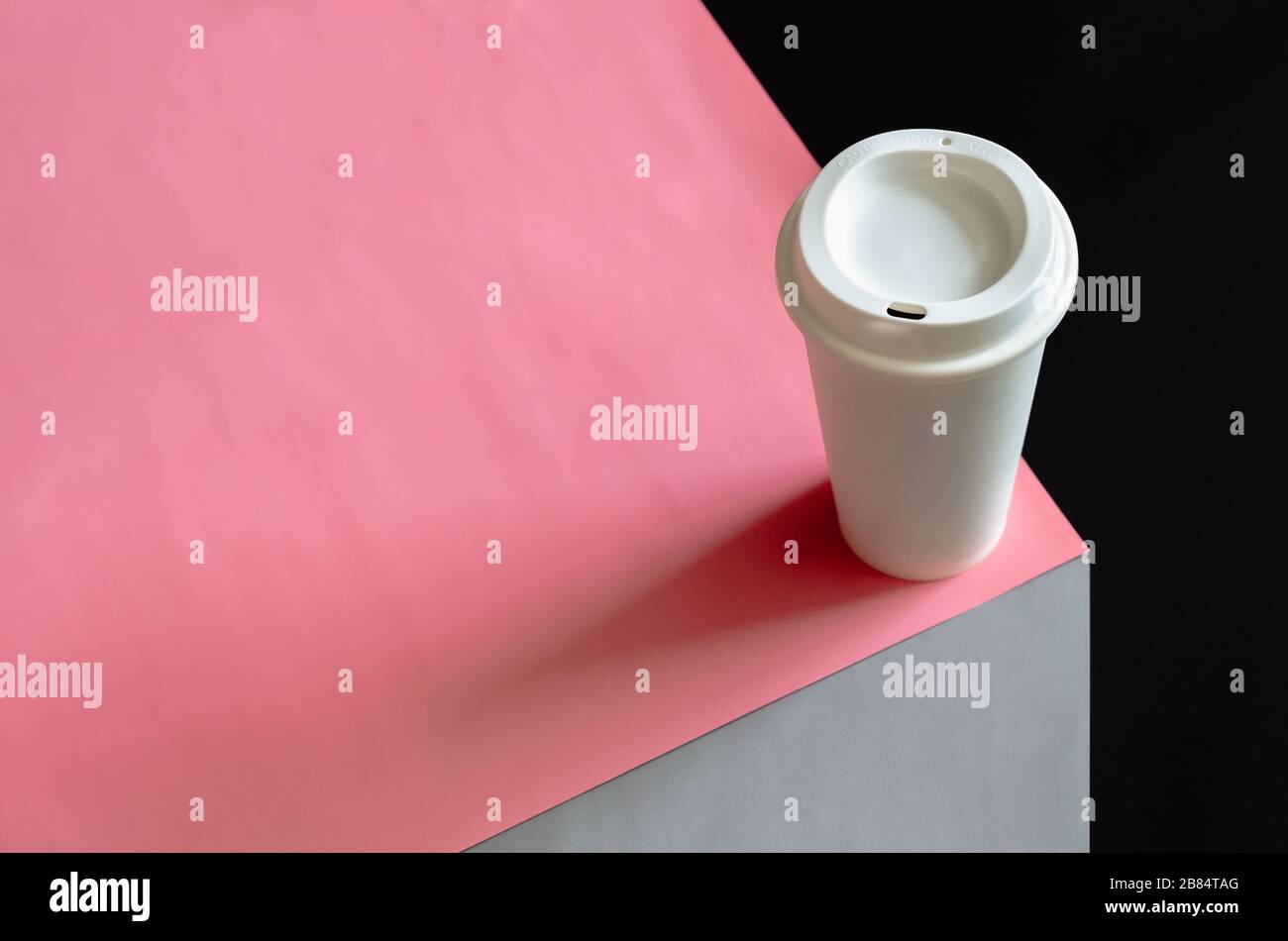 Un verre de café blanc recyclé placé sur du papier couleur rose, gris et noir pour le concept de l'environnement mondial. Banque D'Images