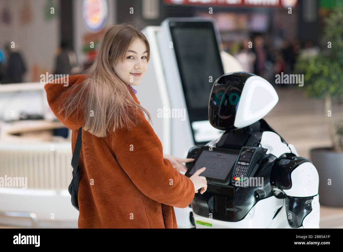 Jeune femme shopper regardant caméra et robot conseiller dans le magasin Banque D'Images