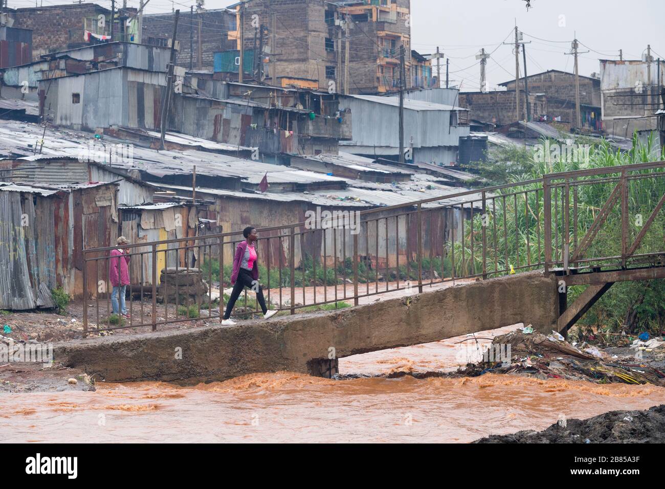 Les gens qui utilisent un pont pour traverser la rivière Mathare, Mathare, Nairobi, Kenya. La rivière Mathare, qui est l'un des affluents de la basi de la rivière Nairobi Banque D'Images