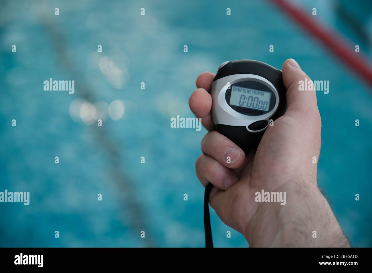 Gros plan d'un autocar non reconnaissable tenant le chronomètre tout en mesurant le temps de nage au bord de la piscine Banque D'Images
