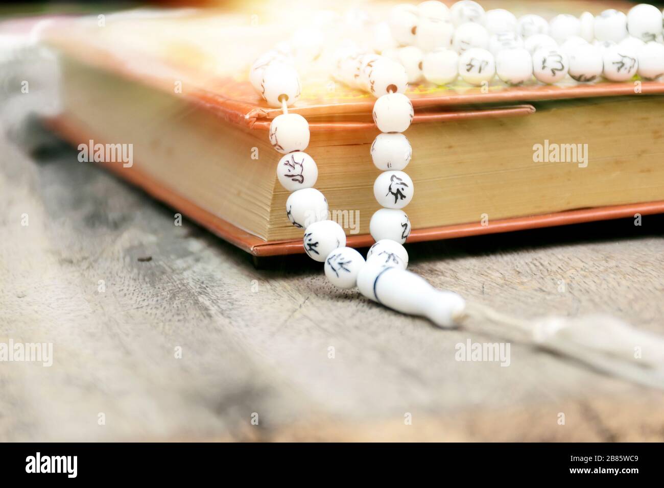 Islam le livre Saint des musulmans, le Coran, est placé sur une table en bois, fond noir, dans la mosquée. DOF. Banque D'Images