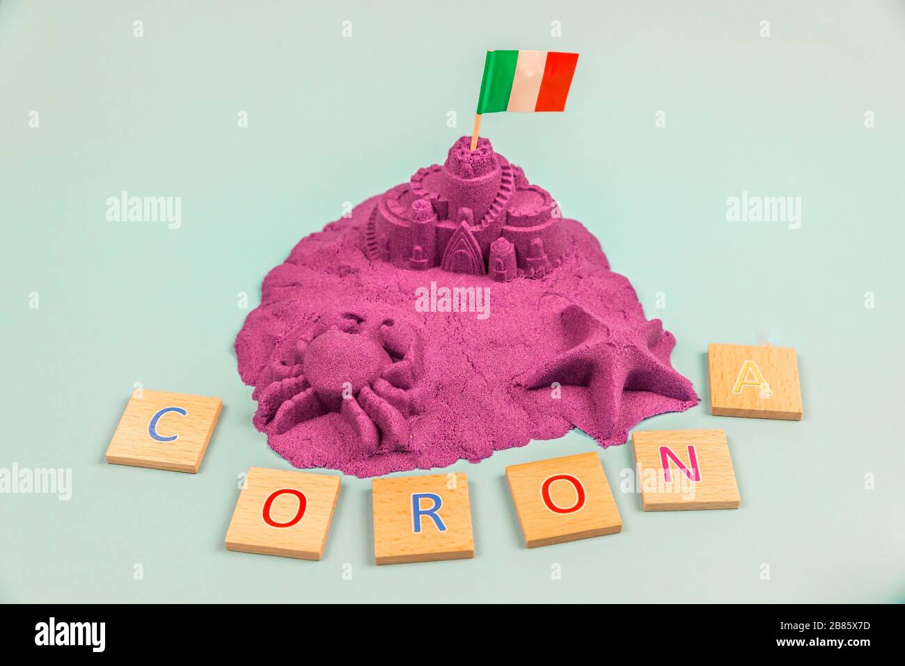 Une île avec drapeau italien sur un château de sable et avec le mot Corona avec des lettres en bois Banque D'Images