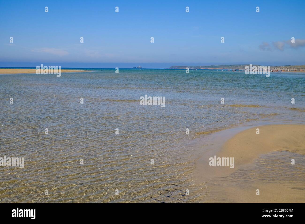 Mer verte bleue entourée d'une plage de sable doré avec touristes et phare en arrière-plan Banque D'Images