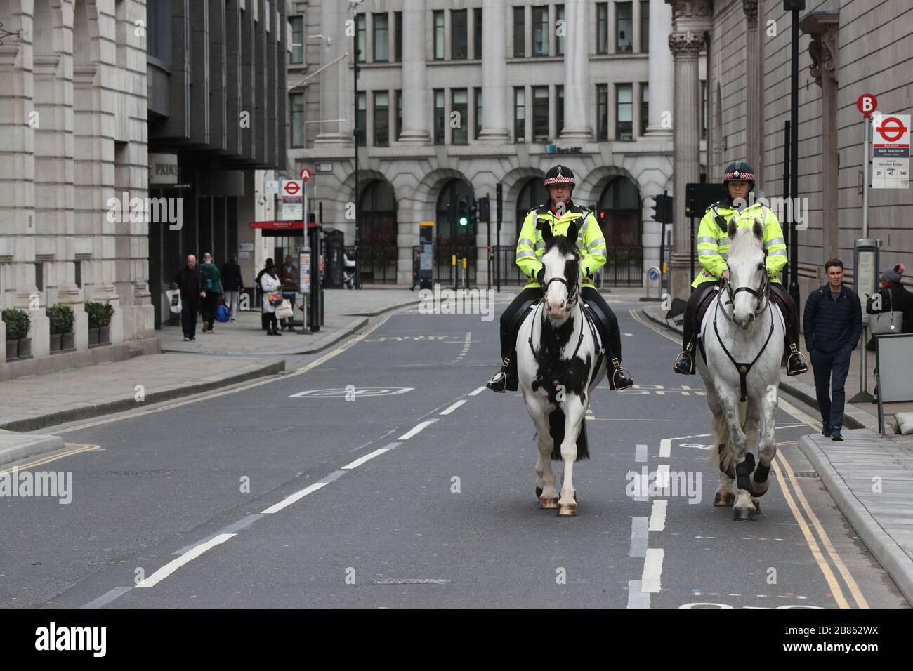 La police montée patrouille une rue calme dans la ville de Londres, alors que le nombre de morts de coronavirus au Royaume-Uni a atteint 144 à 13:00 jeudi, avec environ quatre morts sur 10 jusqu'à présent à Londres. Banque D'Images