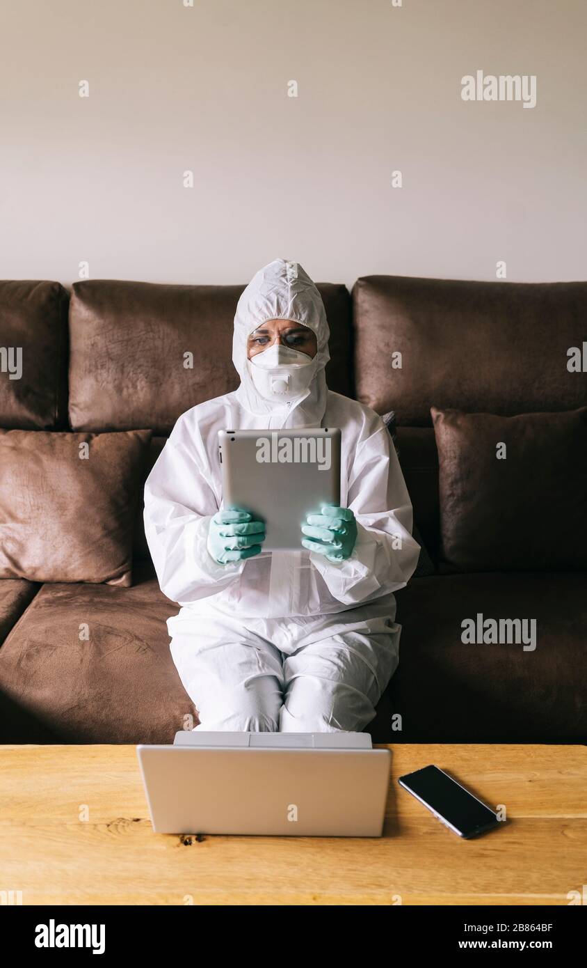 Une femme travaille à la maison avec l'ordinateur portable, la tablette numérique et le téléphone mobile dans le salon, équipé de mesures de sécurité contre un virus preventio Banque D'Images