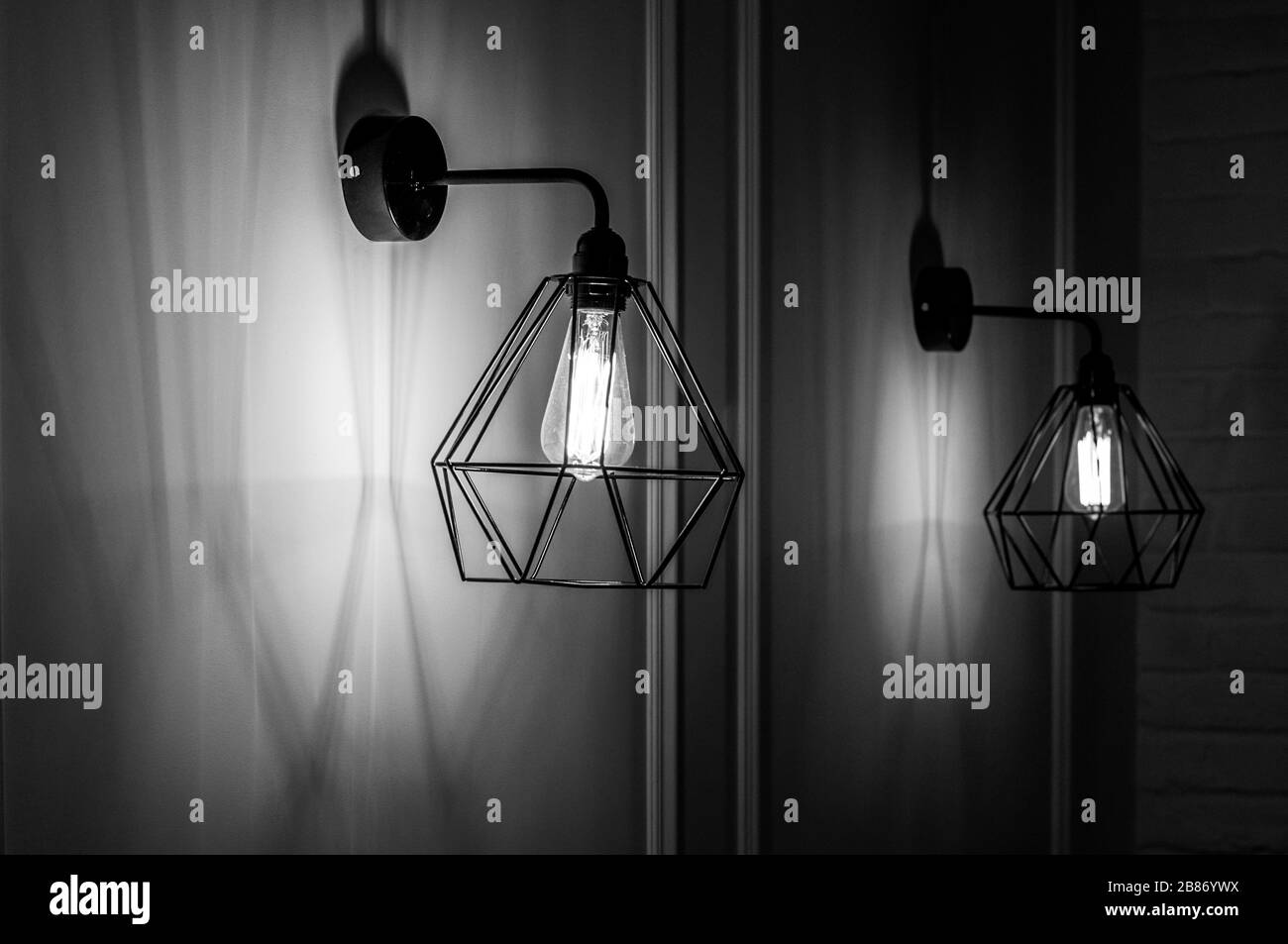 Photo en noir et blanc de la suspension moderne en forme de diamant, abat-jour en fil de fer avec ampoule à l'intérieur. Filament brillant dans des lampes de style minimal Banque D'Images