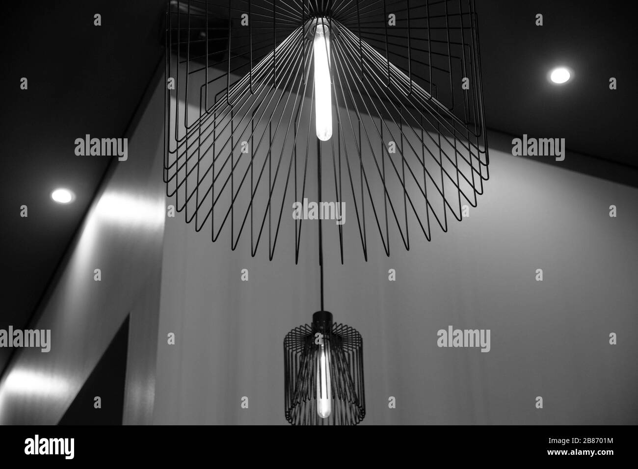 Chandeliers métalliques noirs sur fond de mur. Abat-jour métallique moderne. Lampe avec ampoule longue. Style intérieur urbain. Lignes géométriques Banque D'Images