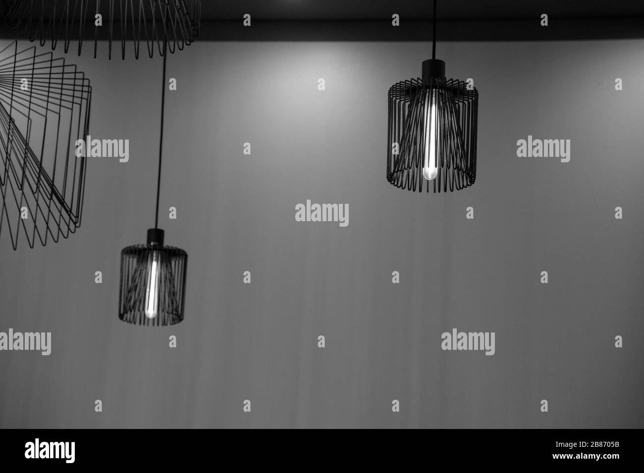 Deux lustres métalliques suspendus sur un fond mural vide. Abat-jour moderne. Lampes avec ampoules longues à l'intérieur. Formes de lignes géométriques. Minimum Banque D'Images