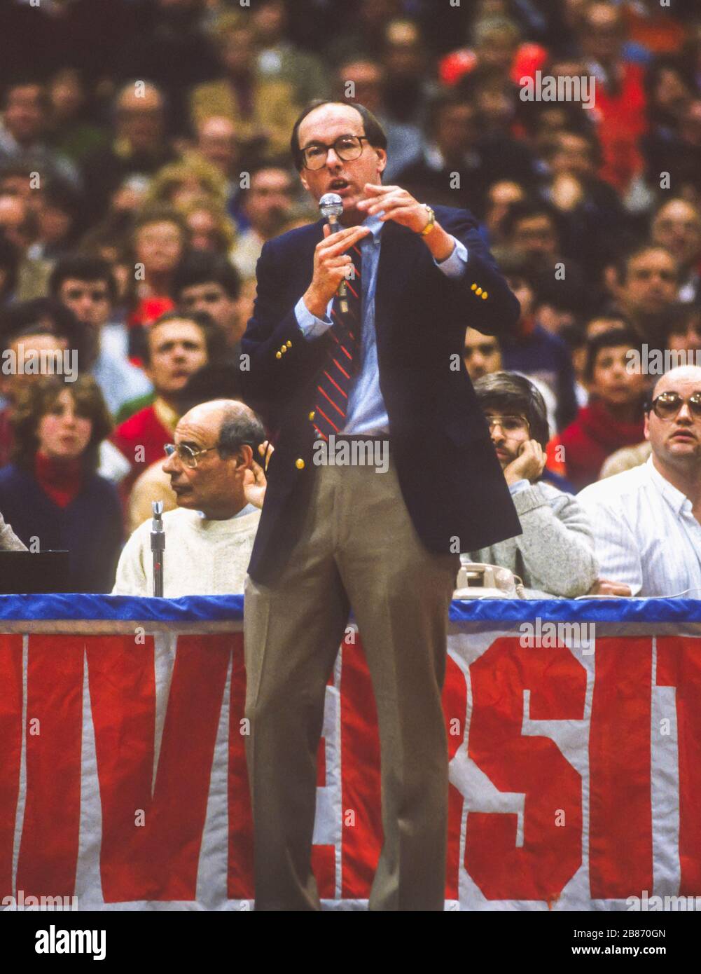 SYRACUSE, NEW YORK, USA, 1985 - le entraîneur de basket-ball de l'Université de Syracuse Jim Boeheim prend le microphone pour avertir la foule de ne pas jeter d'objets sur le terrain pendant le match de Georgetown 1/28/85. Banque D'Images