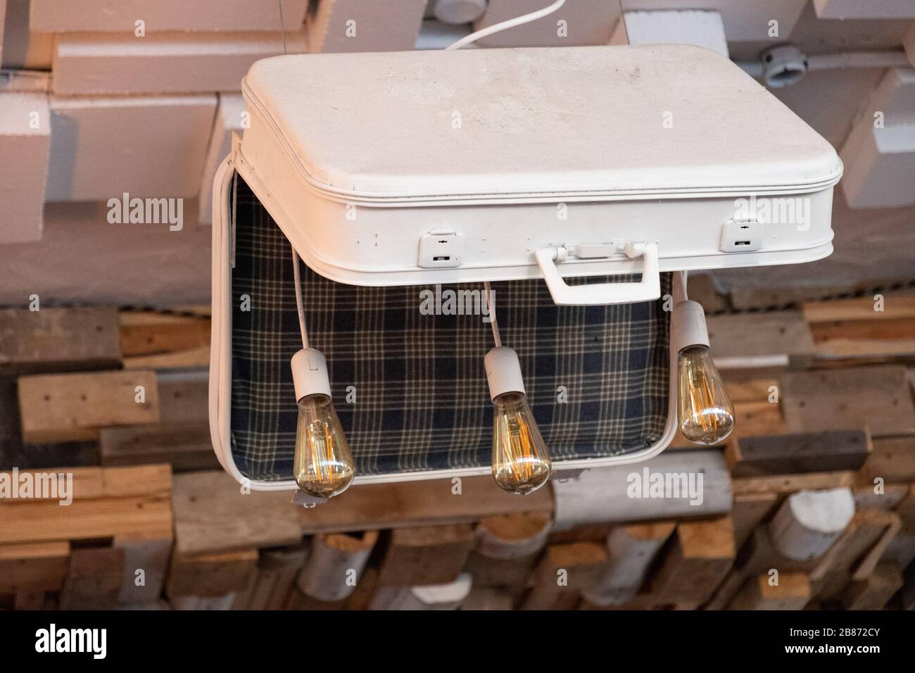 Lustre inhabituel en vieille valise avec trois ampoules en verre Edison à l'intérieur. Valise blanche style rétro avec motif écossais à l'intérieur. Style rétro Banque D'Images