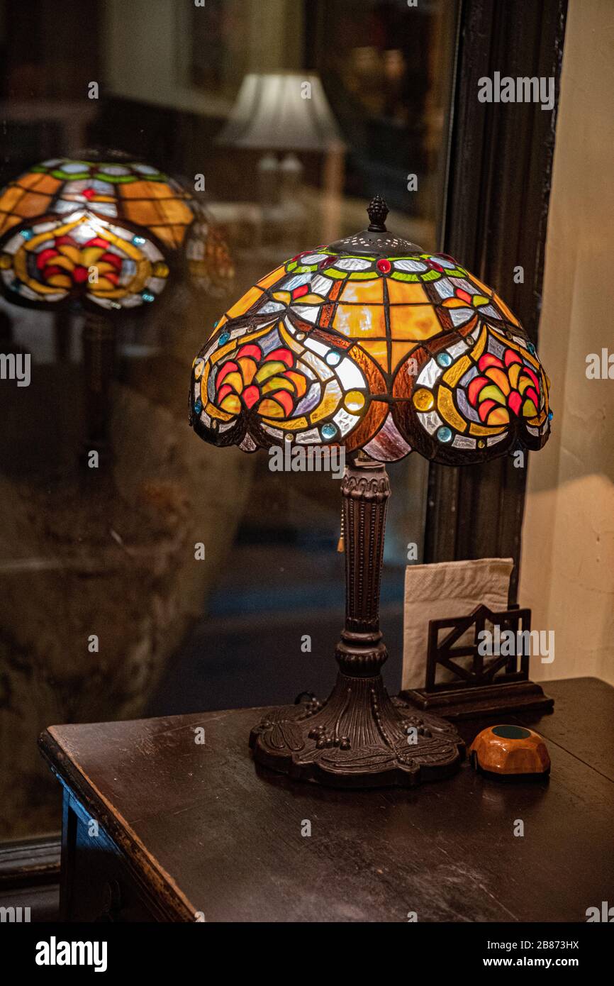 Lampe de table ancienne avec lampadaire en vitrail fermé sur fond sombre flou. Lampe en mosaïque brillant en forme de dôme. Lampe de table vintage. Banque D'Images