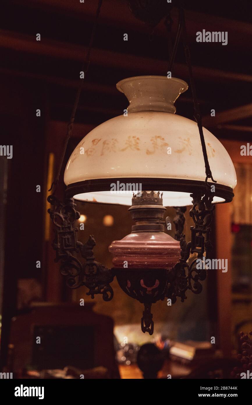 Suspension rétro en forme de lampe au kérosène vintage avec globe à abat-jour en verre blanc mat sur fond sombre et flou. Équipement d'éclairage de suspension Banque D'Images