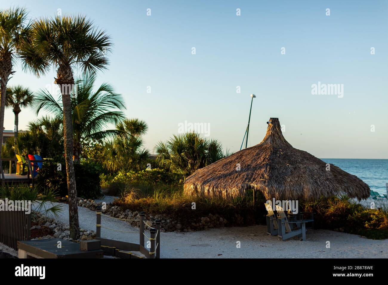 Lido Beach, Floride, États-Unis - 20 mars 2020. Les huttes de palmier sont baignées de lumière tôt le matin lorsque le soleil se lève sur le golfe du Mexique. Banque D'Images