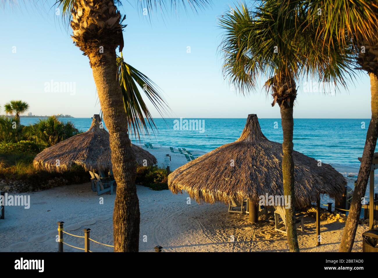 Lido Beach, Floride, États-Unis - 20 mars 2020. Les huttes de palmier sont baignées de lumière tôt le matin lorsque le soleil se lève sur le golfe du Mexique. Banque D'Images