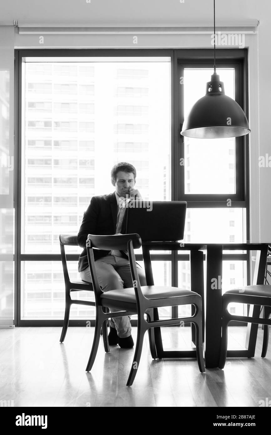 Jeune homme d'affaires beau assis dans la salle à manger près de la cuisine Banque D'Images