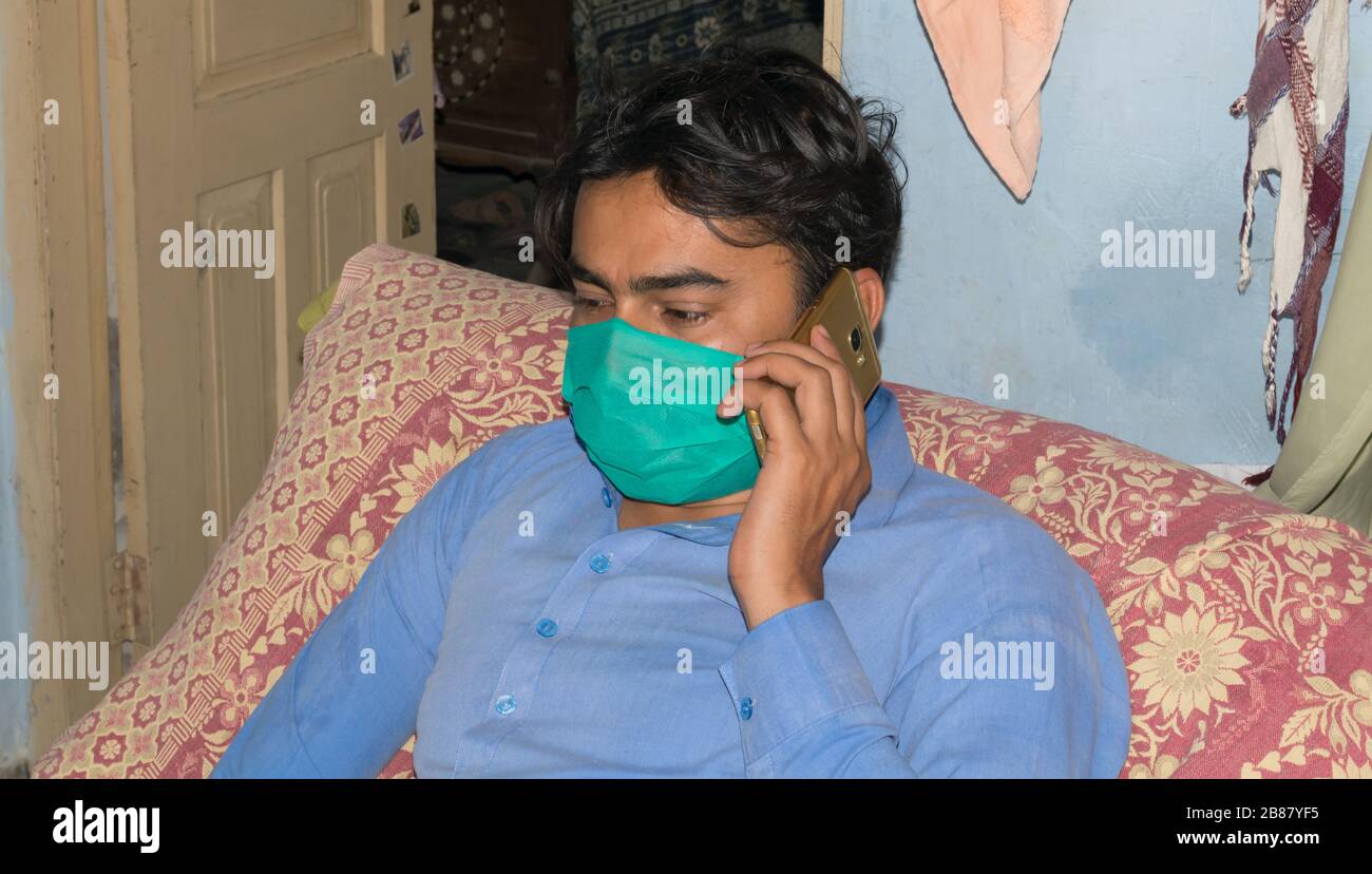 Punjab, Pakistan-20 mars 2020: Un homme avec un téléphone sur le lit portant un masque pour la protection du virus corona (covid-19), la pollution de l'air et le pollen alle Banque D'Images