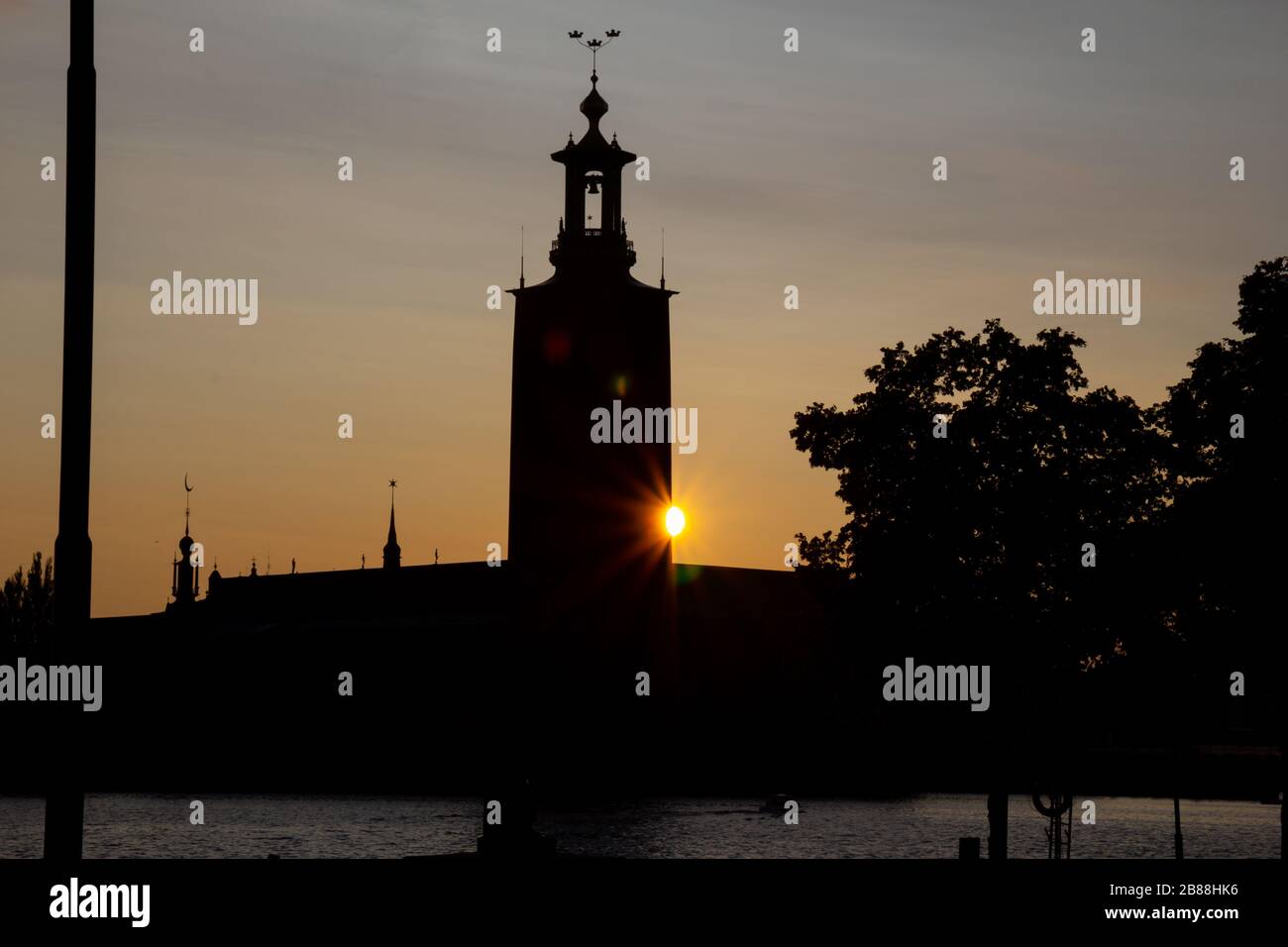 Une lumière du soleil est visible juste derrière l'hôtel de ville de Stockholm alors que le soleil se couche lors d'une chaude soirée d'été dans la capitale de la Suède. Il donne un sentiment de calme. Banque D'Images