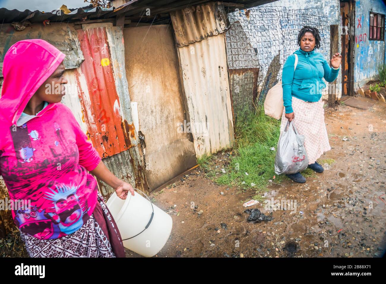 Johannesburg, Afrique du Sud - 5 décembre 2019 - Soweto shanty ville; les femmes parlent dans une rue; jour de pluie. Banque D'Images