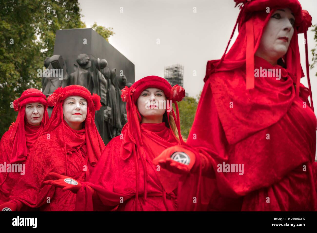 Whitehall, Londres, Royaume-Uni. - 7 octobre 2019 - XR ptotests - rouge 'Brigade' art group, au cours d'une performance de rue, 'la femme de guerre Warld II' en arrière-plan Banque D'Images