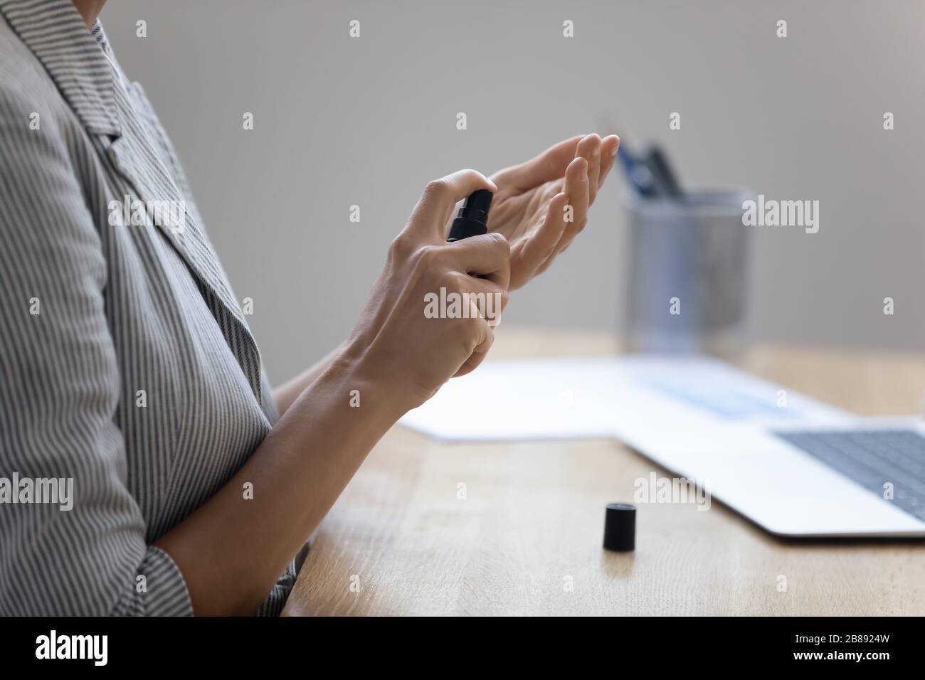 La femme nettoie les mains en vaporisateur de solution désinfectante sur le lieu de travail Banque D'Images