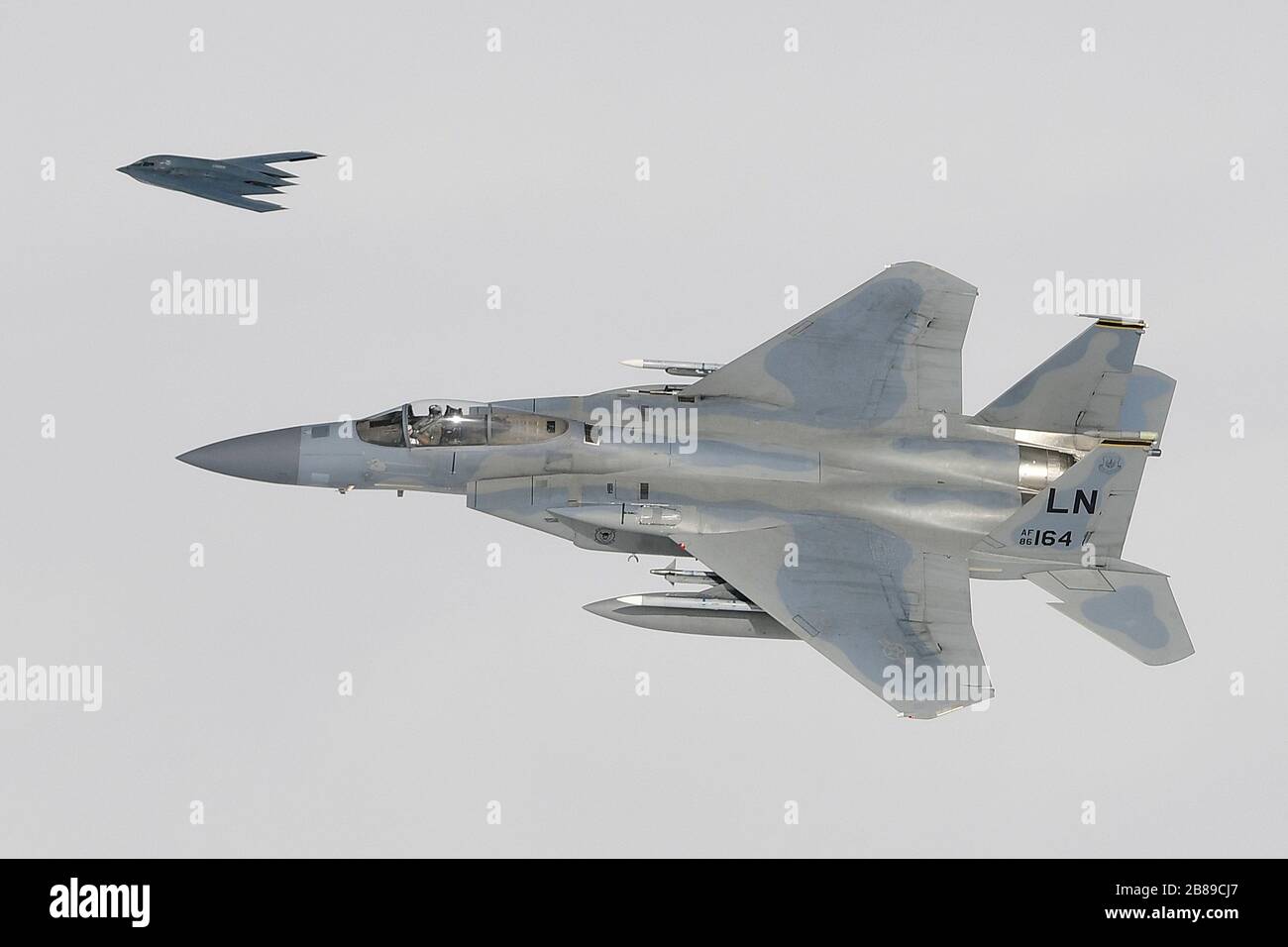 Un bombardier stratégique furtif B-2 A Spirit de l'armée de l'air américaine vole en formation avec des avions de chasse F-15 C Eagle lors d'opérations à l'appui de la Force opérationnelle de bombardement Europe 20-2 le 16 mars 2020 au-dessus de Keflavik, Islande. Banque D'Images