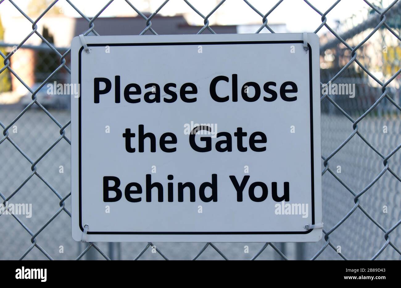 Vue du panneau blanc « Please Close the Gate Behind You » à l'entrée du parc des chiens de Vancouver Banque D'Images