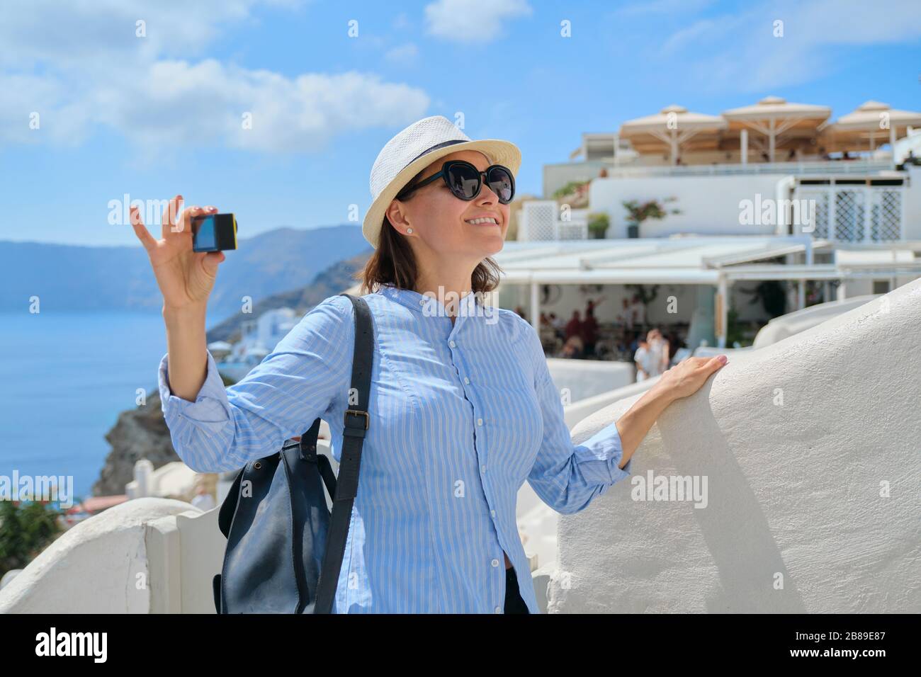 Femme Voyage vlogue voyager dans le village grec d'Oia sur l'île de Santorin, tournage de la vidéo de caméra aktion, fond blanc architecture, mer, ciel dans le clo Banque D'Images