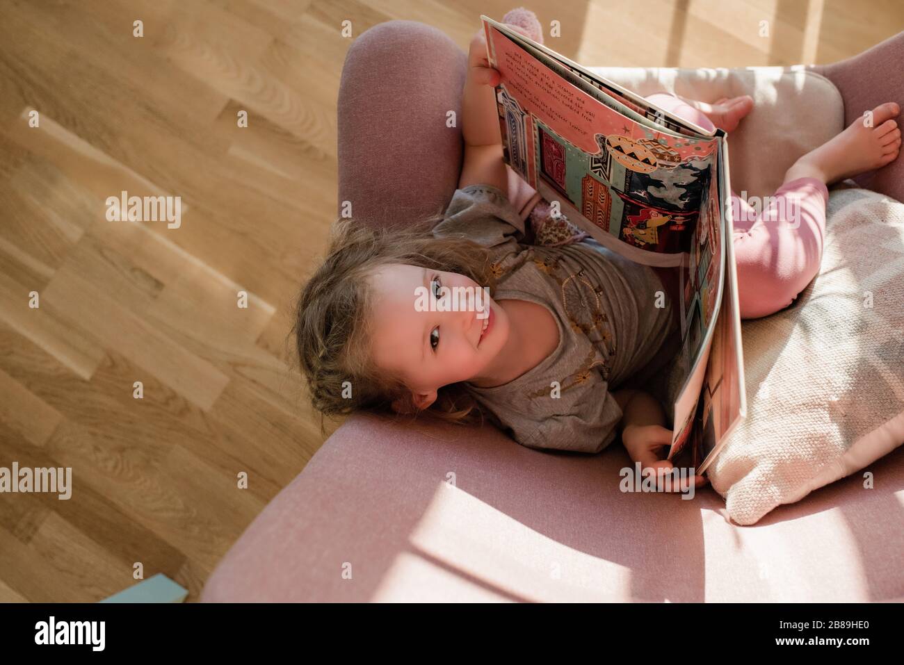 vue de la partie supérieure de la jeune fille regardant la lecture s'est assise sur une chaise à la maison Banque D'Images