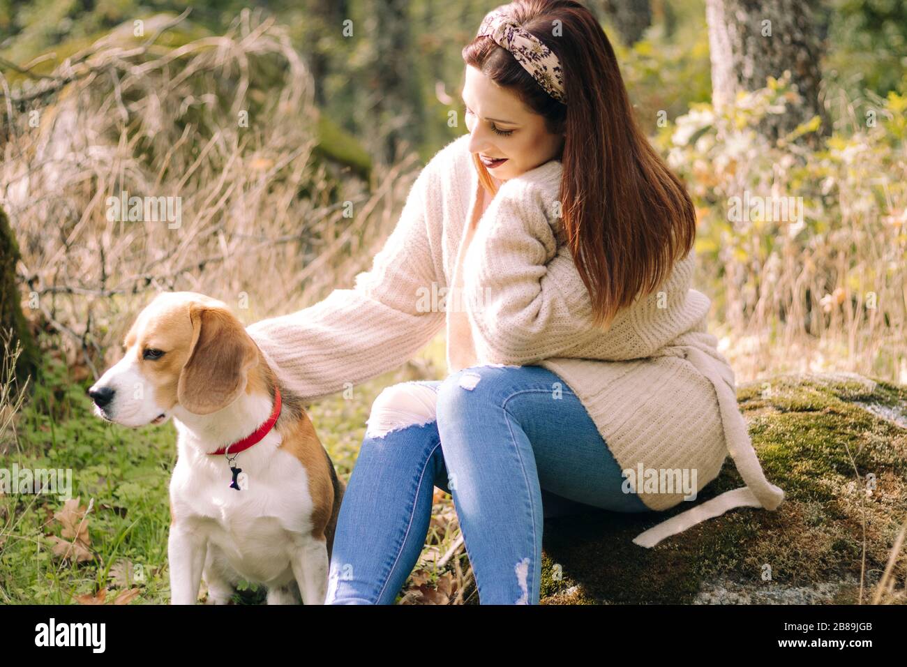 Jeune femme souriante, assise à côté de son chien pendant une promenade Banque D'Images