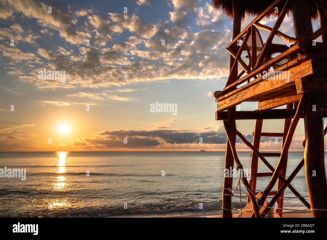 Lever du soleil sur les plages tropicales de la Riviera Maya près de Cancun, au Mexique, avec tour de sauveteur surplombant la mer des Caraïbes. Banque D'Images
