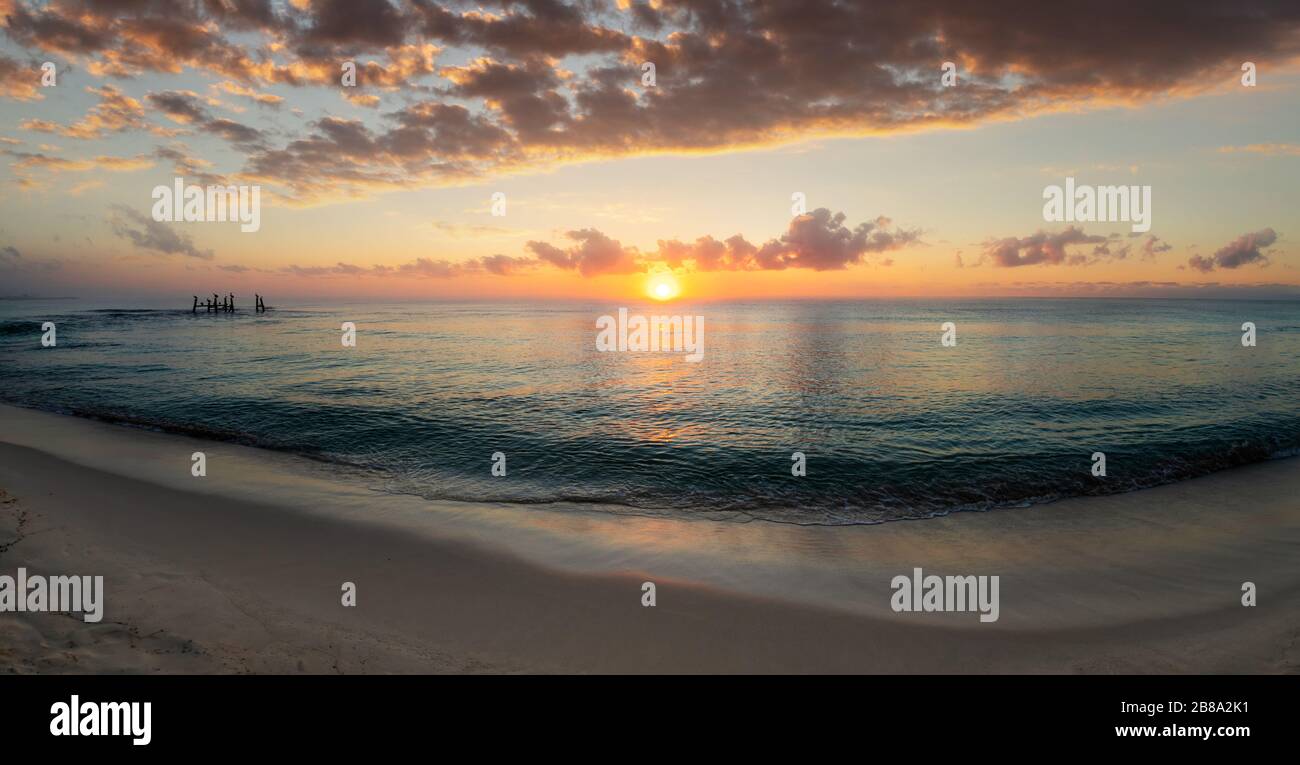 Panorama d'un magnifique lever de soleil au bord des plages de sable de la Riviera Maya à Cancun, au Mexique, avec des reflets dorés sur la mer des Caraïbes. Banque D'Images