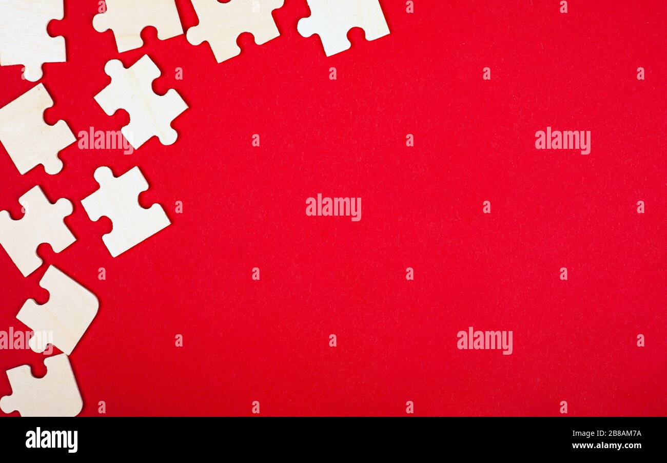 mosaïque de puzzle en bois sur un fond rouge vue du dessus gros plan espace de copie. Banque D'Images