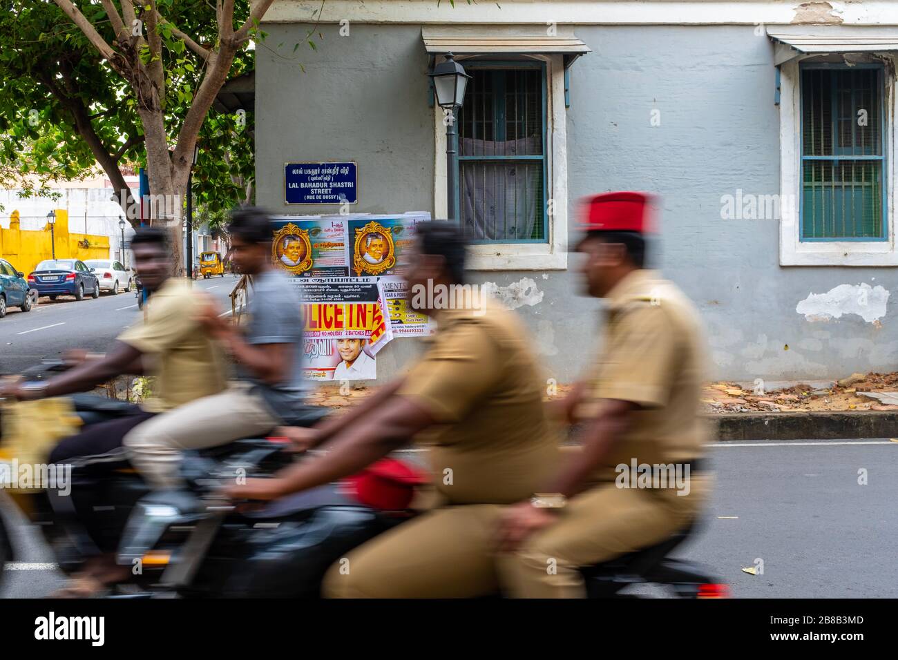 Pondichéry, Inde - 17 mars 2018 : hommes non reconnaissables devant un mur gris et un panneau de rue sur deux scooters avec flou de mouvement Banque D'Images