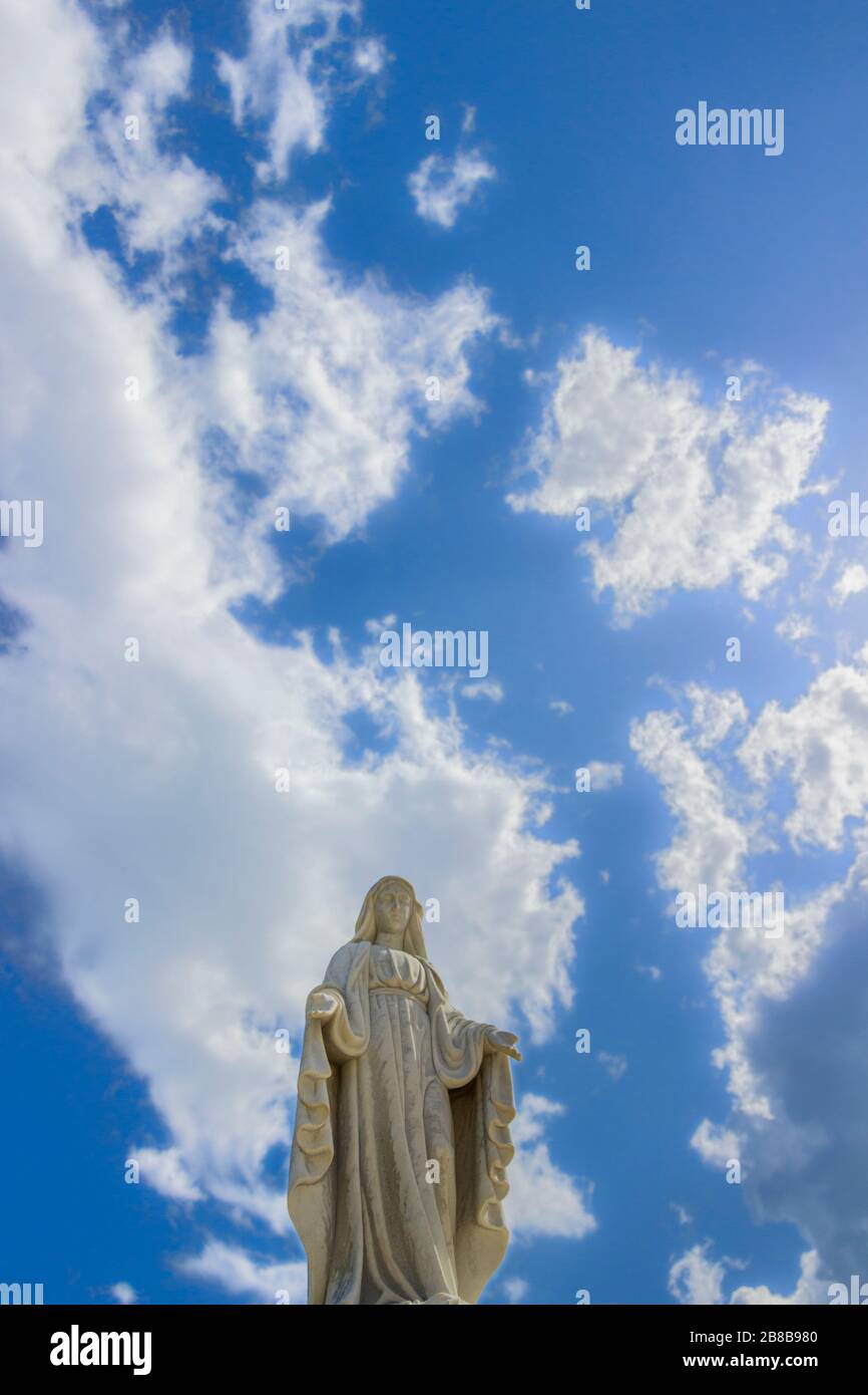Statue de la Vierge Marie avec beau ciel avec nuages en arrière-plan. Banque D'Images