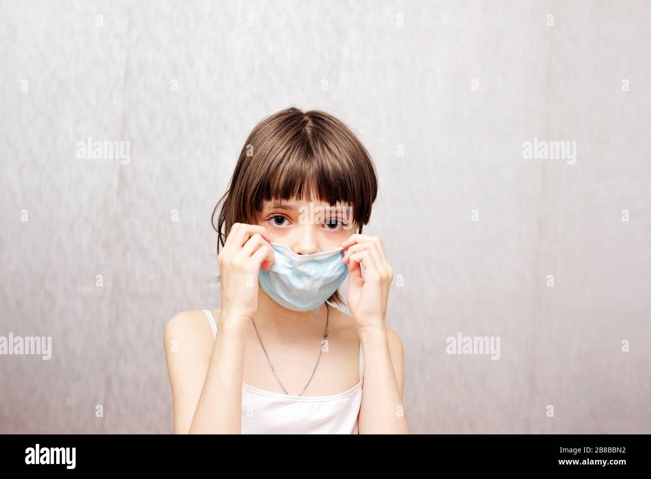 La fille ajuste son masque médical protecteur sur son visage. Banque D'Images