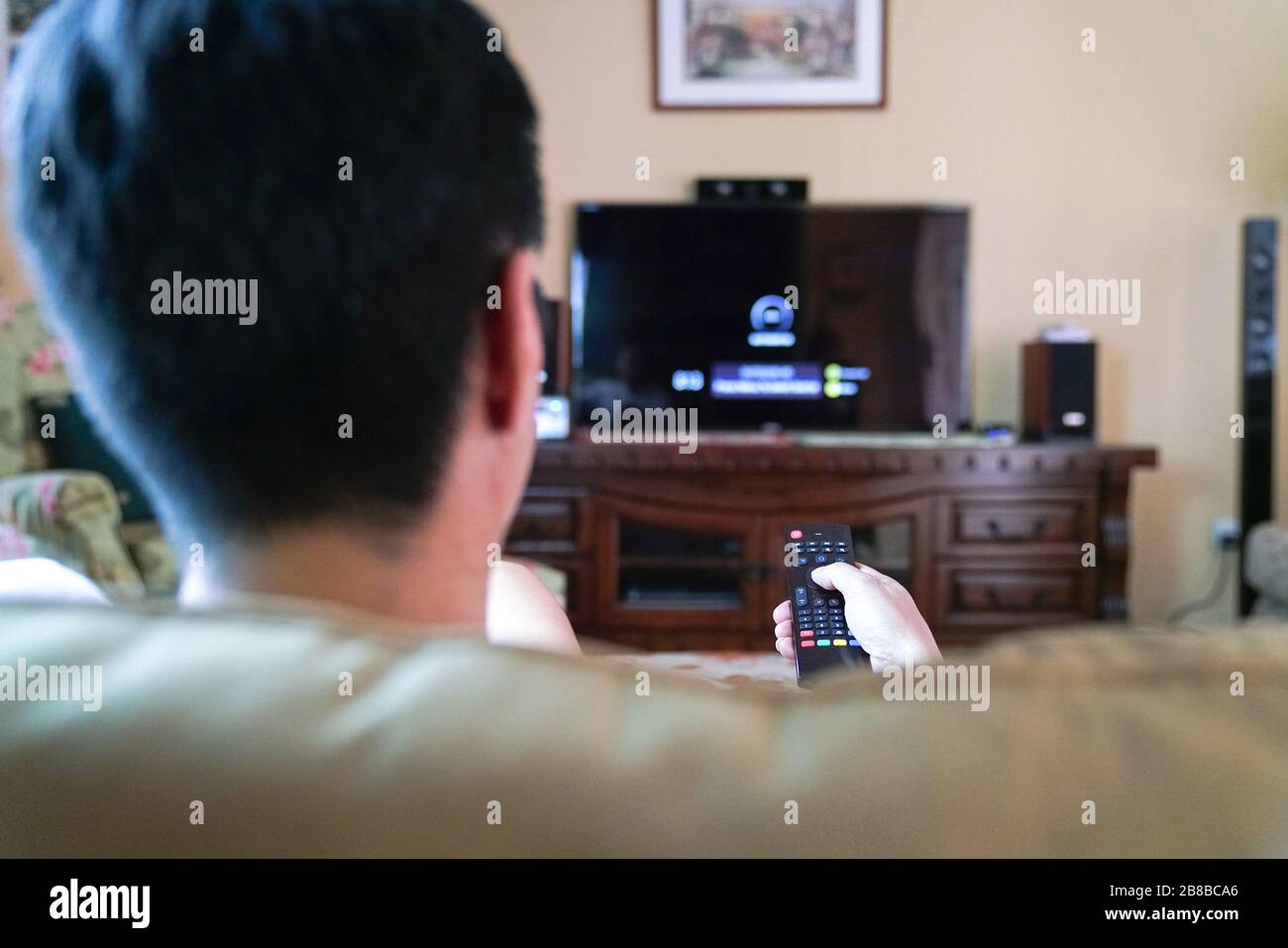 Homme regardant la télévision en se concentrant sur ses mains sur la télécommande. Divertissement à domicile ou concept de séjour à la maison. Banque D'Images