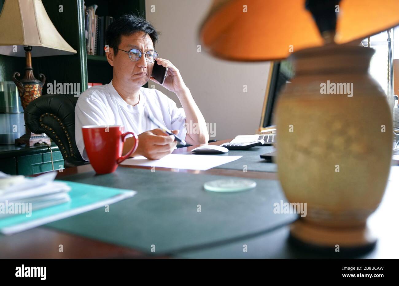 Homme travaillant sur son téléphone portable, travaillant à la maison. Expression mécontente. Banque D'Images